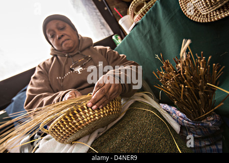 Femme tissant Gullah sweetgrass paniers à l'Historic Charleston City Market sur Market Street à Charleston, SC. Banque D'Images