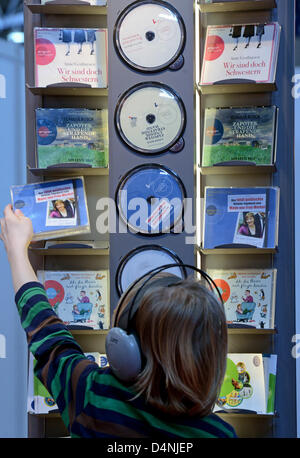 Un garçon est assis avec un casque dans un livre audio stand lors de la foire du livre de Leipzig, Allemagne, 17 mars 2013. La foire se termine après quatre jours avec environ 168,000 visiteurs. Plus de 2000 éditeurs de 43 pays se sont présentés avec leurs nouvelles versions à la foire. Photo : Hendrik Schmidt Banque D'Images