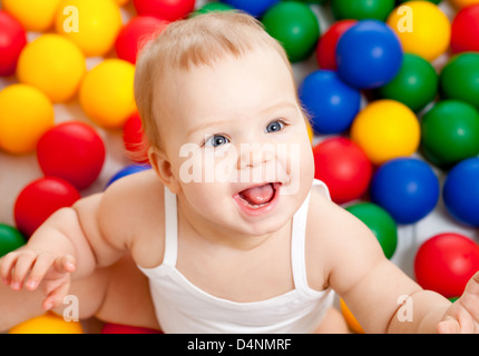 Portrait of a smiling infant assis parmi les boules colorées Banque D'Images