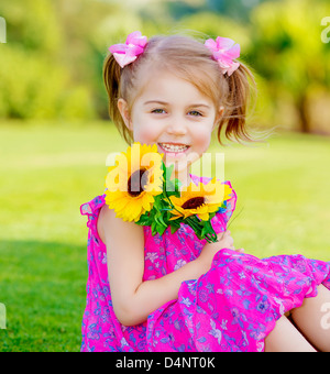 Happy baby girl playing outdoor, cute child holding fresh fleurs de tournesol, kid s'amuser dans le parc d'été, belle enfant