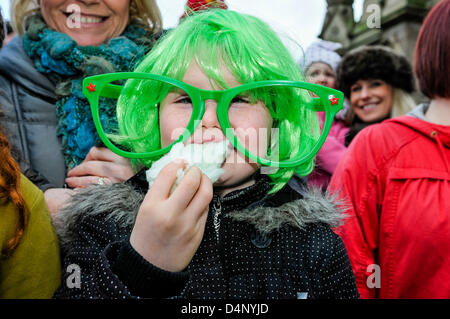 Enfant vêtu d'une perruque verte et des verres de couleur verte, mange de la barbe à papa en regardant l'Assemblée Saint Patrick's Day Parade à Belfast. Banque D'Images