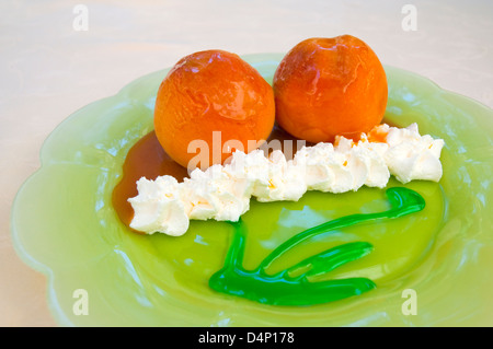 Dessert : deux pêches au four avec de la crème chantilly, sauce caramel et menthe poivrée. Voir de très près. Banque D'Images