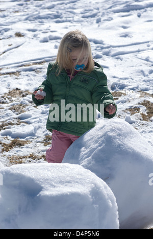 Tout-petit enfant bébé fille blonde marcher et jouer dans paysage de neige - la montagne d'hiver Banque D'Images