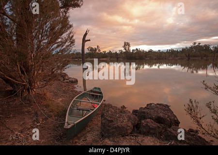 Rivière Balonne avec nuages rose du crépuscule reflète dans les eaux calmes près de St George, dans l'arrière-pays australien - et canoë sur rocky bank Banque D'Images