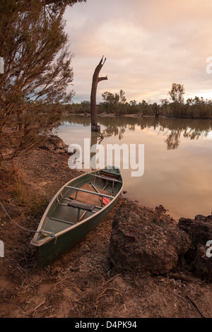 Rivière Balonne avec nuages rose du crépuscule reflète dans les eaux calmes près de St George, dans l'arrière-pays australien - et canoë sur rocky bank Banque D'Images