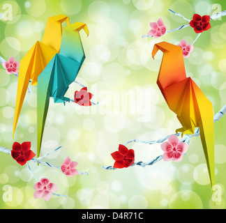 L'origami perroquets sur une des branches des arbres avec des fleurs sur fond vert Banque D'Images