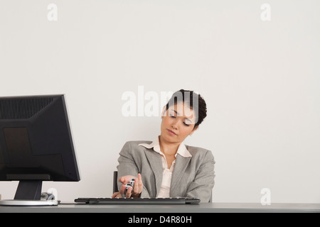 Young businesswoman holding Yin Yang balls at desk Banque D'Images