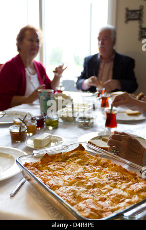 Vieux couple dans la conversation tout en ayant le petit déjeuner turc avec borek et thé chaud, accompagné d'olives, confitures, beurre. Banque D'Images