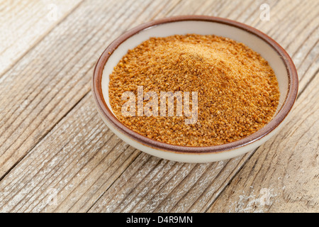 Petit bol en céramique de sucre non raffiné de cocotier contre un arrière-plan en bois peint blanc grunge Banque D'Images
