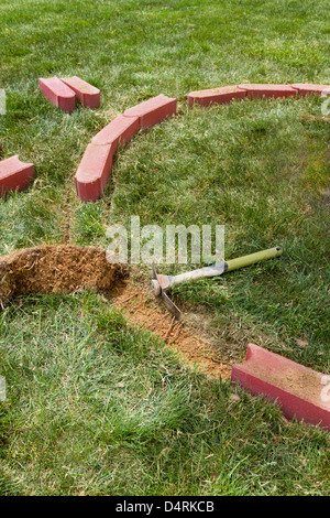 L'installation de bordures en briques avec un côté briques arrondies en supprimant l'herbe. Banque D'Images