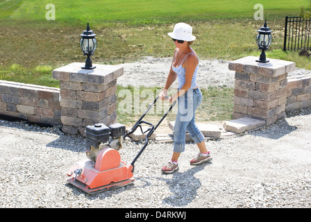 Femme avec chapeau le compactage de base patio sous le soleil. Banque D'Images