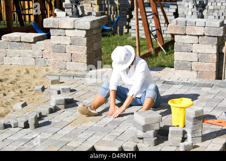 Femme avec chapeau paving patio sous le soleil. Banque D'Images