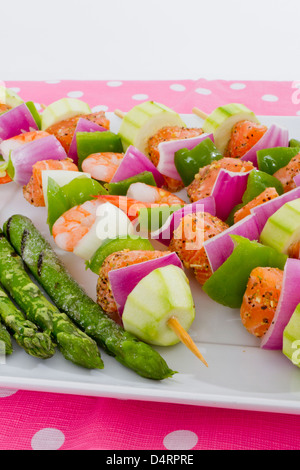 Cubes de saumon et de crevettes a complimenté avec légumes sur les brochettes. Prêt à cuire. Oignons rouges, courgettes, poivrons, asperges. Banque D'Images