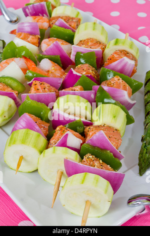 Cubes de saumon et de crevettes a complimenté avec légumes sur les brochettes. Prêt à cuire. Oignons rouges, courgettes, poivrons, asperges. Banque D'Images