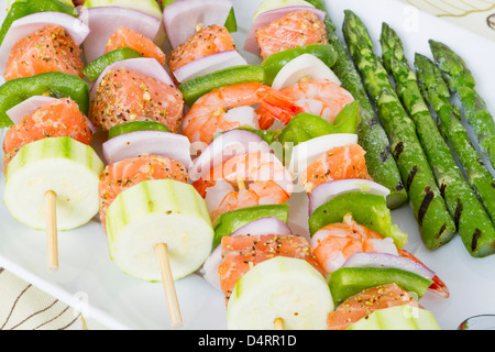 Cubes de saumon et de crevettes a complimenté avec légumes sur les brochettes. Prêt à cuire. Oignons rouges, courgettes, poivrons, asperges. Banque D'Images