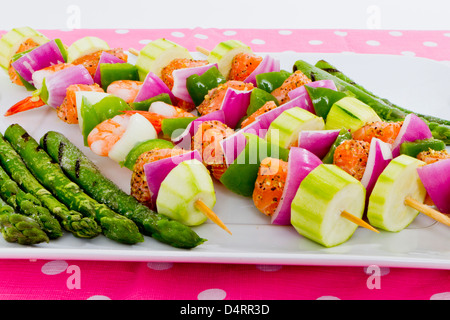 Cubes de saumon et de crevettes a complimenté avec légumes sur les brochettes. Prêt à cuire. Oignons rouges, courgettes, poivrons, asperges Banque D'Images