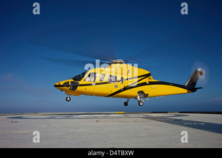 Un hélicoptère Sikorsky S-76 hélicoptère utilitaire de l'hélisurface sur une plate-forme pétrolière. Banque D'Images