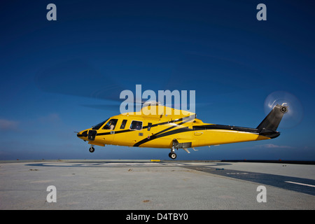 Un hélicoptère Sikorsky S-76 hélicoptère utilitaire de l'hélisurface sur une plate-forme pétrolière. Banque D'Images