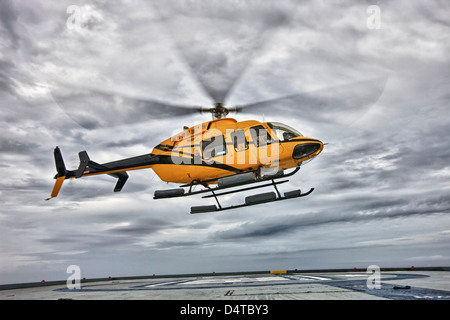 Un hélicoptère Bell 407 utility se prépare à atterrir sur l'héliport d'une plate-forme pétrolière. Banque D'Images