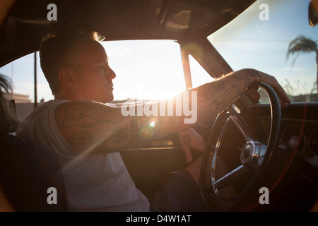 Homme conduisant vintage car au coucher du soleil Banque D'Images