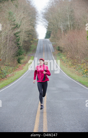 Woman running on rural road Banque D'Images