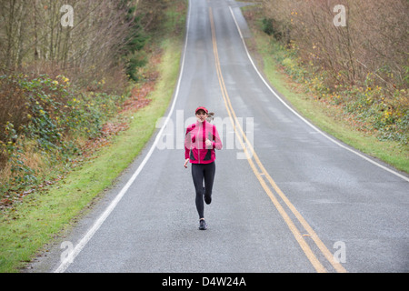 Woman running on rural road Banque D'Images