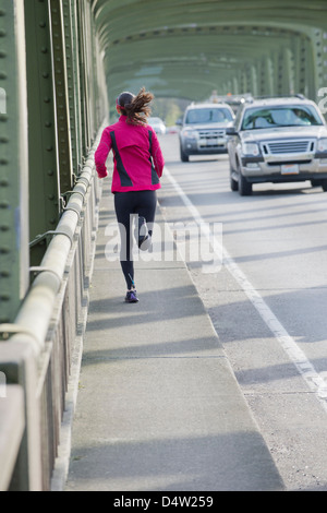 Woman running on urban bridge Banque D'Images