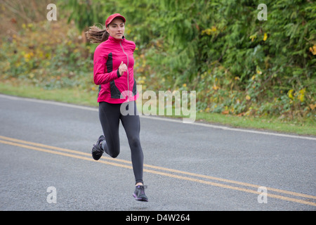 Woman running on rural road Banque D'Images