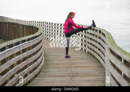 Runner stretching on wooden dock Banque D'Images