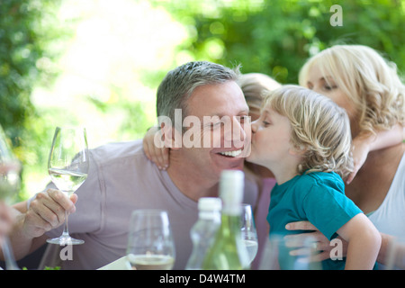 Boy kissing père à table outdoors Banque D'Images