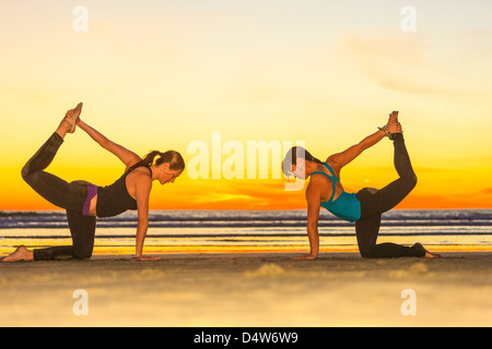 Women practicing yoga on beach Banque D'Images