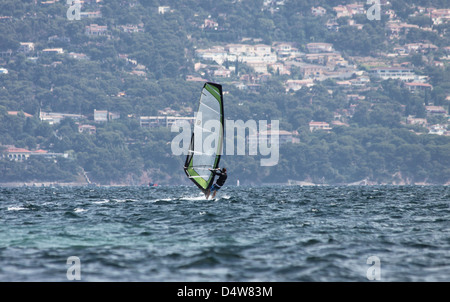 Une planche avec un voile vert sur un fond bleu foncé. Prises à Hyères, France. Banque D'Images