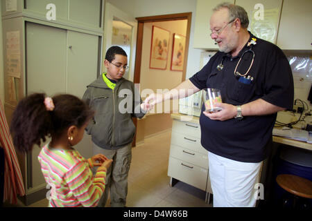 (Dossier) - Un fichier dpa photo datée du 27 mars 2009 montre un pédiatre distribuant des bonbons aux deux enfants à sa pratique à Cologne, Allemagne. Photo : Rolf Vennenbernd Banque D'Images
