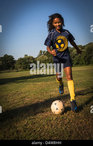 Girl playing soccer in field Banque D'Images