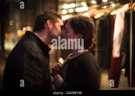 Couple kissing on city street at night Banque D'Images