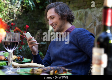 Man using cell phone at table outdoors Banque D'Images