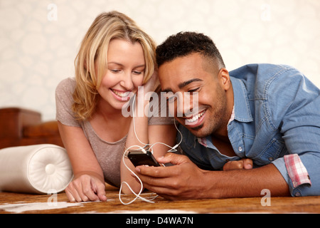 Couple listening to headphones on bed Banque D'Images