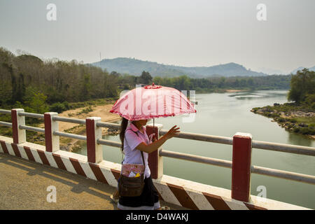 15 mars 2013 - Luang Prabang, Luang Prabang, Laos - filles de l'École de traverser le pont nam Oh sur l'autoroute 13 à Luang Prabang province. L'asphaltage de l'autoroute 13 de Vientiane à près de la frontière chinoise a changé le mode de vie dans les régions rurales du Laos. Les villageois près de Luang Prabang l'habitude d'avoir à prendre des bateaux peu fiable qui a duré trois heures aller-retour pour se rendre de la maison au centre touristique de Luang Prabang, maintenant ils prennent un aller-retour de 40 minutes en bus. Au nord de Luang Prabang, ouvrant ainsi la voie publique a été l'occasion pour la Chine d'utiliser le Laos en tant que point de transbordement. La marchandise chinoise va désormais throu Banque D'Images