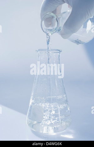 Scientist pouring liquid into beaker Banque D'Images