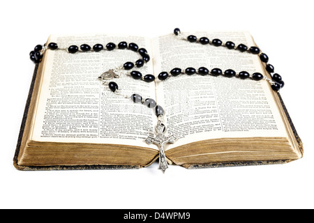 Chapelet et croix couchée sur une page de la bible isolé sur un fond blanc. Banque D'Images