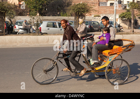 Un cycle rickshaw avec un homme et des jeunes enfants en tant que passagers dans les rues d'Amritsar, Punjab, en Inde. Banque D'Images