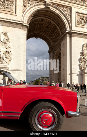 Vétéran Mercedes rouge voiture en face de l'Arc de Triomphe à Paris ; L'Arc de Triomphe de l'Étoile à Paris Banque D'Images