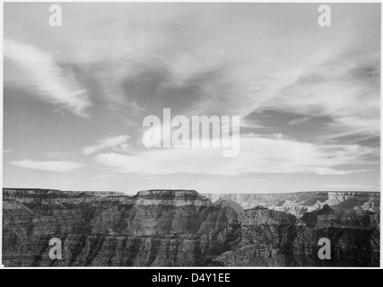 La photographie d’Ansel Adams capture l’immense bord du canyon du Grand Canyon, avec un horizon bas et un ciel nuageux, soulignant la grandeur et la beauté naturelle du parc. Banque D'Images