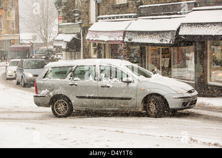 Les voitures qui circulent dans Ambleside dans la neige, Lake District, UK. Banque D'Images