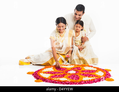 La famille du sud de l'Inde faisant un rangoli de fleurs à Onam Banque D'Images