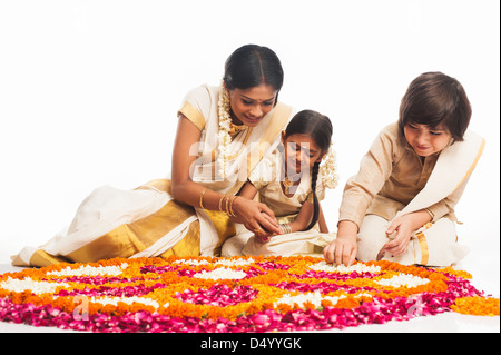 La famille du sud de l'Inde faisant un rangoli de fleurs à Onam Banque D'Images