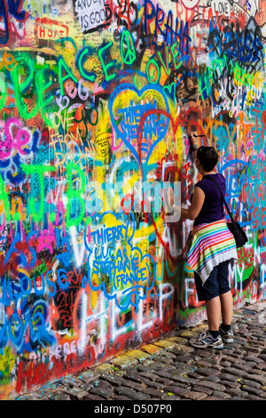 Une jeune fille touristiques ajoute à la graffiti Wall John Lennon à Prague, Prague, République tchèque,Česká Republika,Europe Banque D'Images