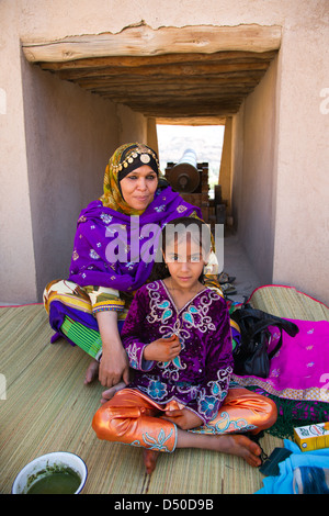 Un commerçant du marché et sa fille dans des tenues colorées dans le fort de Nizwa, Oman Banque D'Images