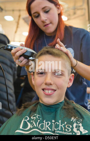 New York, USA. 19 mars 2013. JOSEPH ROSENTHAL, 11, de Merrick, a sa tête rasée par KELSEY BAZAREWSAKI, une junior qui prend à la cosmétologie Calhoun High School, à St. Baldrick's événement de collecte de fonds à Calhoun. L'école de Long Island a dépassé son objectif de recueillir 50 000 $ pour la recherche sur le cancer. De plus, de nombreuses queues coupées seront donnés à Locks of Love Foundation, qui recueille des dons de cheveux pour faire des perruques pour les enfants qui ont perdu leurs cheveux à cause de raisons médicales. Credit : Ann E Parry / Alamy Live News Banque D'Images