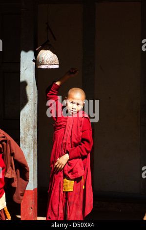 Un jeune apprenti moine dans un monastère près de Hsipaw, Myanmarr sonne pour appeler la communauté à déjeuner dans la salle à manger. Banque D'Images